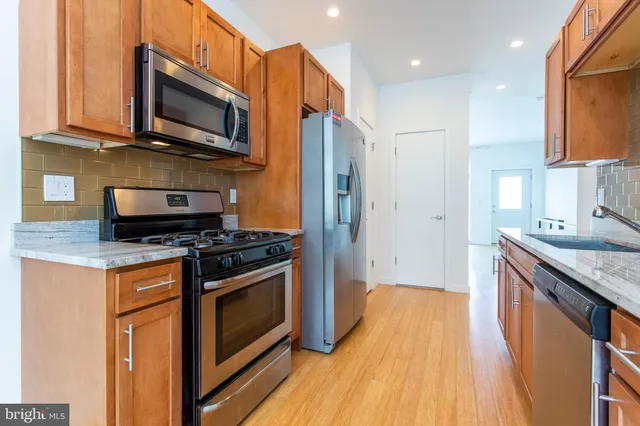 a kitchen with stainless steel appliances granite countertop a sink stove and refrigerator