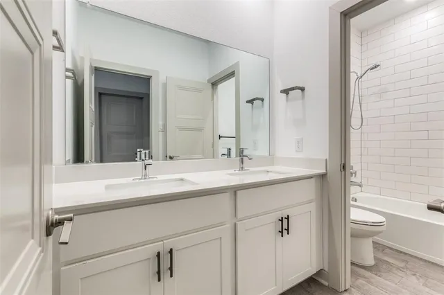 a bathroom with a double vanity sink toilet mirror and bathtub
