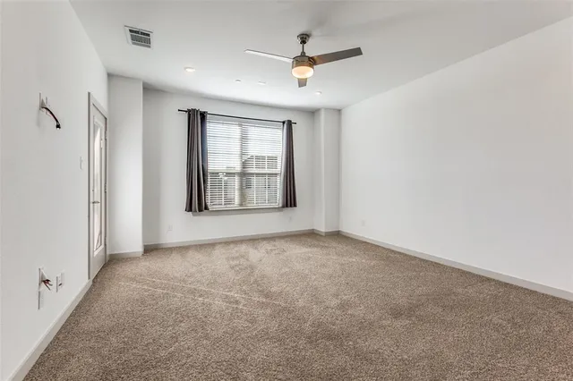 an empty room with windows and ceiling fan