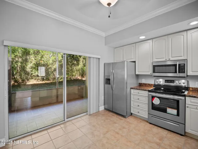 a kitchen with stainless steel appliances granite countertop a refrigerator a stove a sink and a large window with the garden view