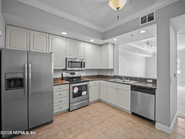 a kitchen with stainless steel appliances granite countertop a stove a sink and a refrigerator