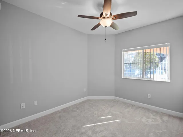 an empty room with a window and a fan