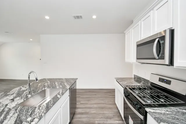 a kitchen with stainless steel appliances granite countertop a sink stove and cabinets