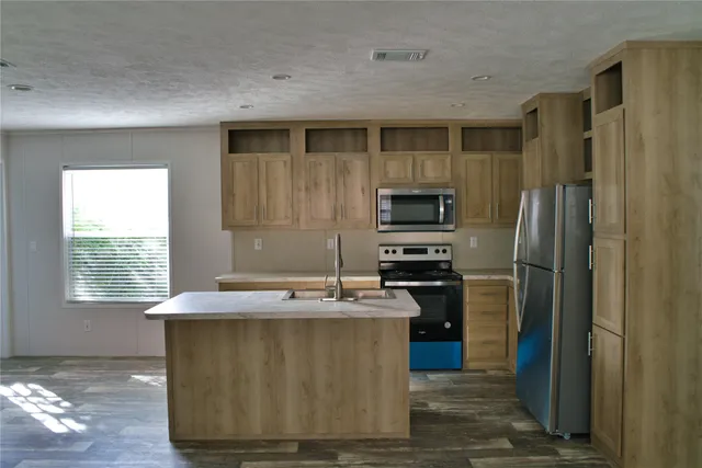 a kitchen with kitchen island a counter top space stainless steel appliances and a window