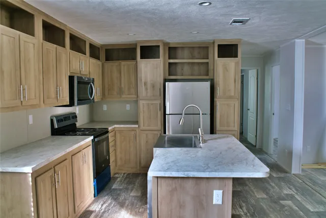 a kitchen with stainless steel appliances granite countertop a kitchen island a stove a sink a refrigerator and cabinets