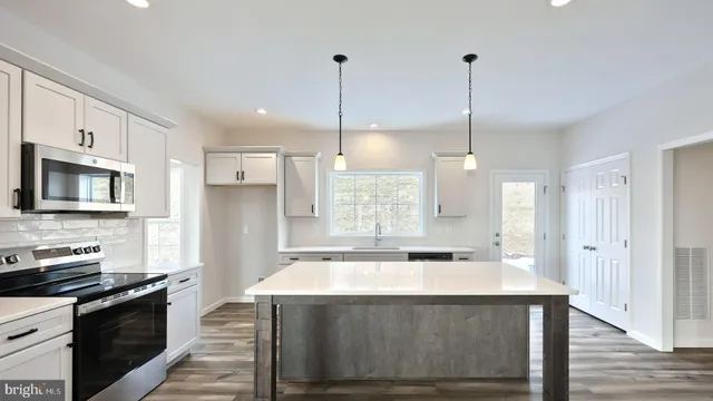 a kitchen with kitchen island a sink stainless steel appliances and cabinets