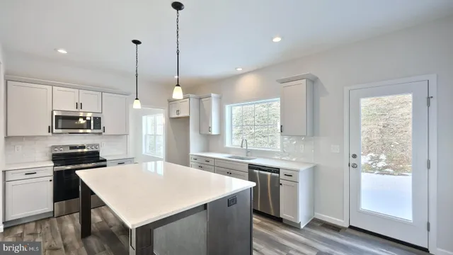 a kitchen with stainless steel appliances a stove a sink a refrigerator a center island a stove and a window