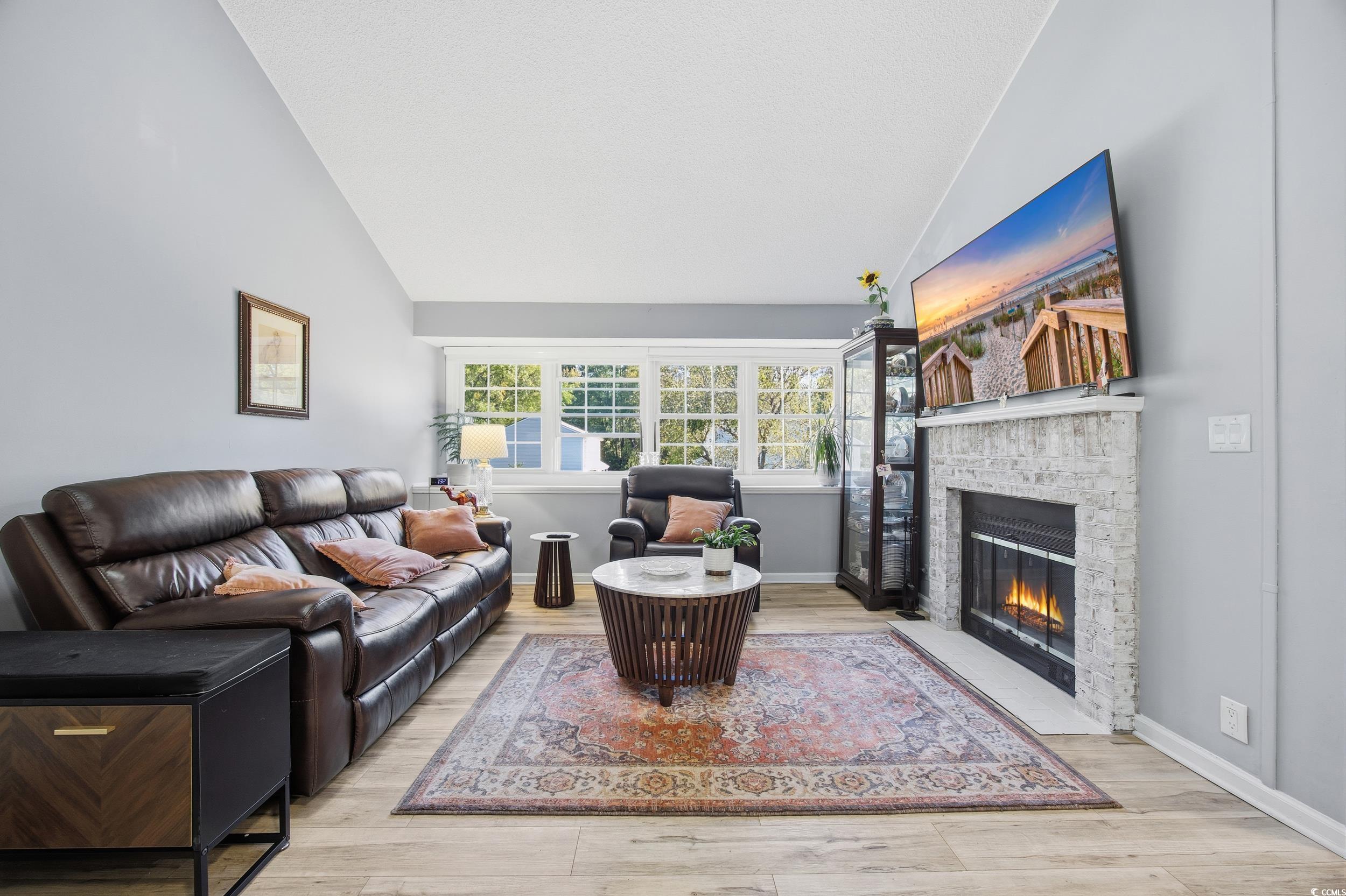 1200 Benna Drive, Unit 1C Myrtle Beach, SC 29577 - Photo 8 of 37 Living area featuring a brick fireplace, light wood finished floors, and high vaulted ceiling