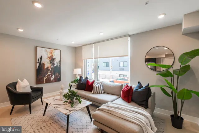a living room with furniture a potted plant and a large window