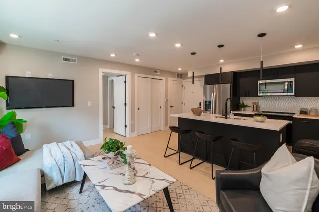 a living room with kitchen view and a flat screen tv