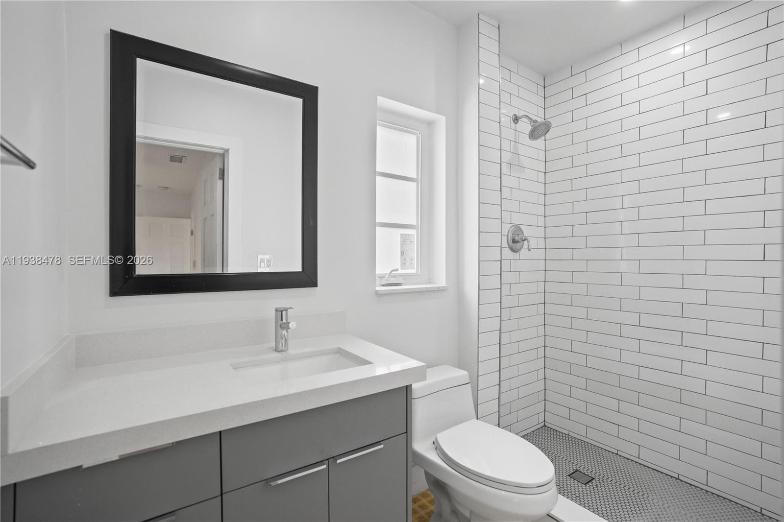 550 Northeast 68th Street, Unit 550 Miami, FL 33138 - Photo 8 of 15 a bathroom with a toilet a sink a shower and mirror