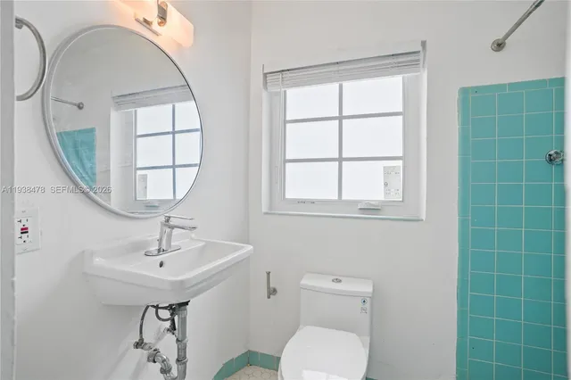 a bathroom with a toilet a sink a window and mirror