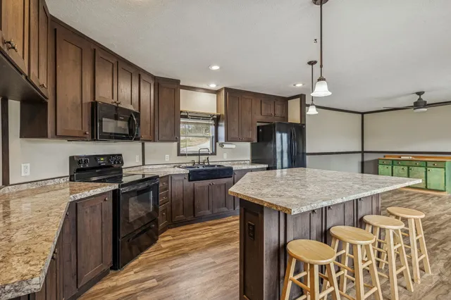 a kitchen with a stove a sink a kitchen island with wooden cabinets and chairs