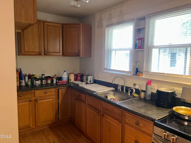 a kitchen with granite countertop a sink cabinets stainless steel appliances and a window