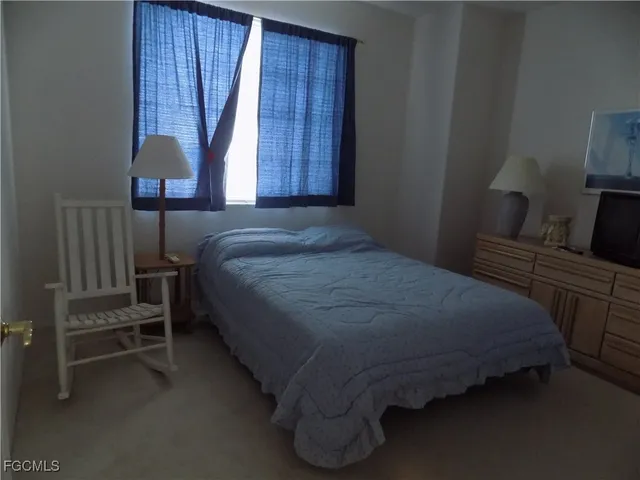 a bedroom with a bed and a lamp on dresser