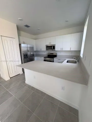 a kitchen with stainless steel appliances a sink a stove a microwave a refrigerator a counter top space and cabinets