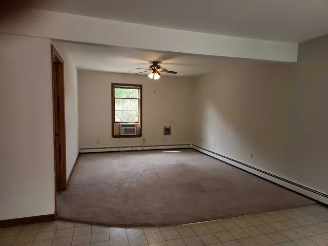 an empty room with windows and ceiling fan