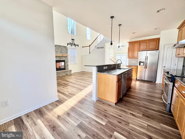 a kitchen with stainless steel appliances granite countertop a stove and a wooden floor