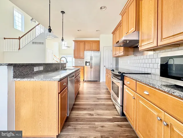 a kitchen with stainless steel appliances granite countertop a sink and a stove