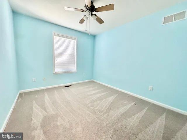 an empty room with ceiling fan and window