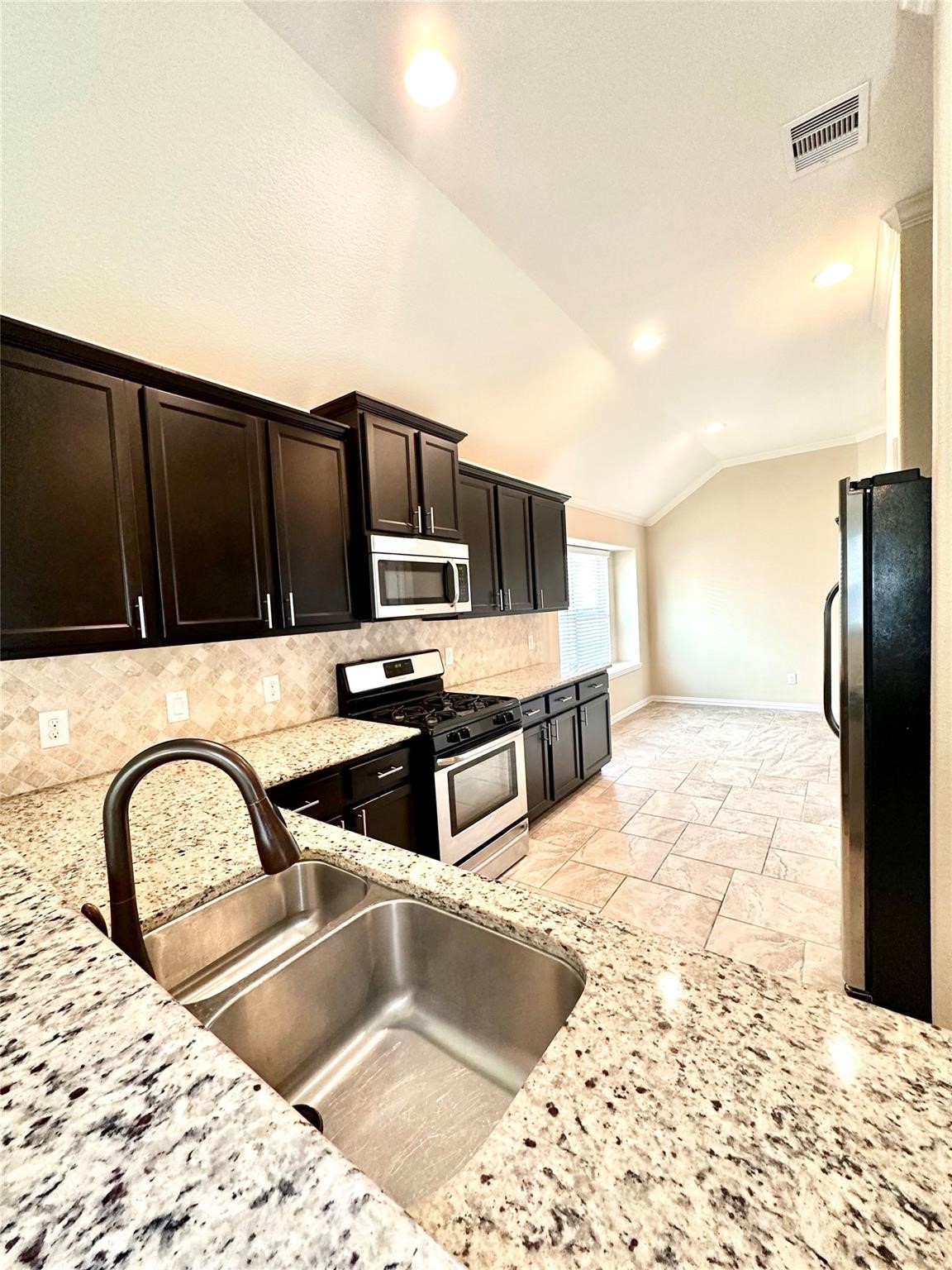 14818 Raleigh's Meadow Court Cypress, TX 77433 - Photo 2 of 17 a kitchen with stainless steel appliances kitchen island granite countertop a refrigerator and a stove top oven