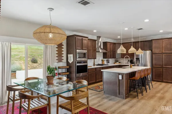 a kitchen with stainless steel appliances a table chairs and a refrigerator