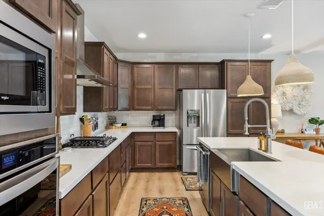 a kitchen with stainless steel appliances kitchen island granite countertop a table chairs microwave and sink