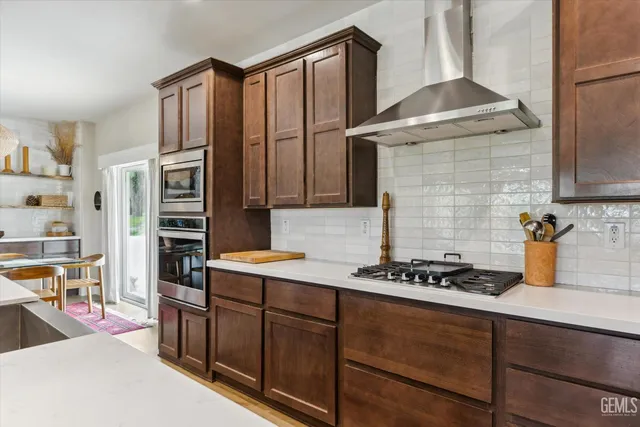 a living room with stainless steel appliances kitchen island granite countertop a table chairs and a refrigerator