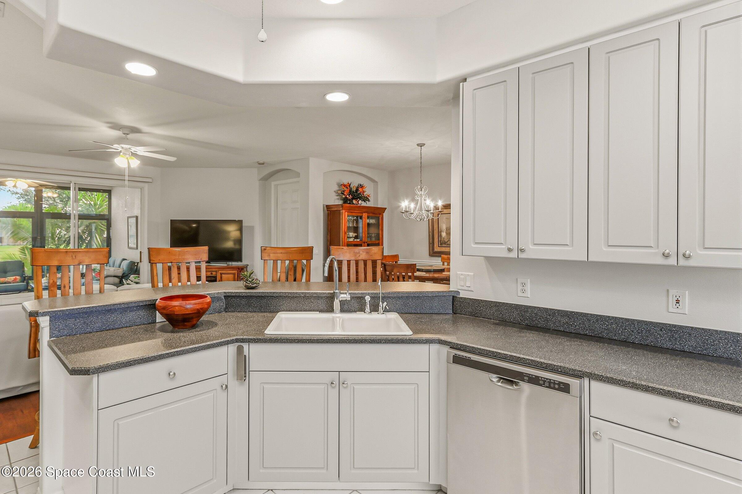 1825 Ficus Point Drive Melbourne, FL 32940 - Photo 16 of 48 a kitchen with stainless steel appliances granite countertop a sink dishwasher and white cabinets with wooden floor