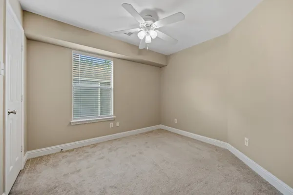 an empty room with a chandelier fan and windows