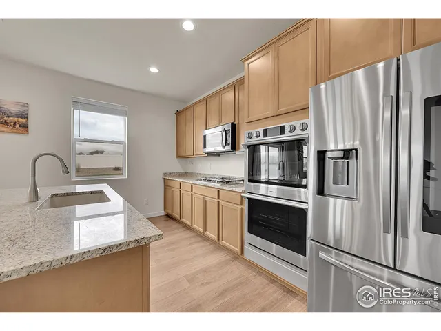 a kitchen with granite countertop a refrigerator stove and sink