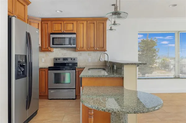 a kitchen with stainless steel appliances granite countertop a refrigerator a stove and a sink with wooden floor