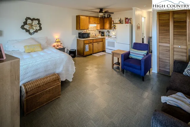 a bedroom with a bed a flat tv screen and a bookshelf with wooden floor