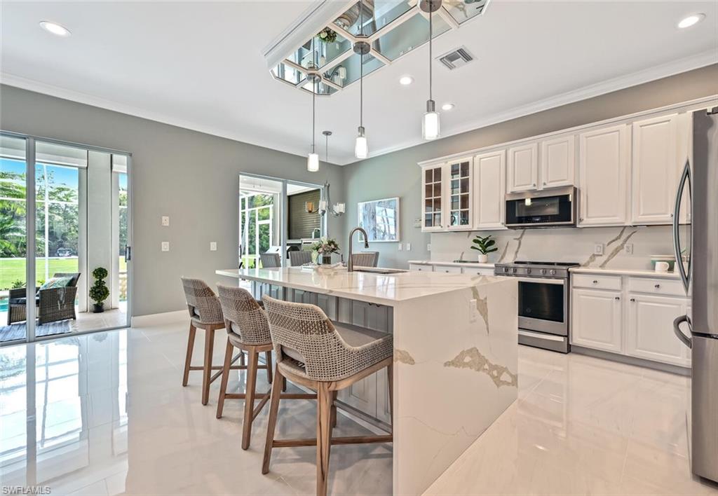 5616 Lago Villaggio Way Naples, FL 34104 - Photo 9 of 43 a kitchen with a white cabinets and chairs