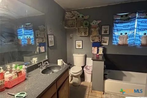 a bathroom with a granite countertop sink a toilet a mirror and shower