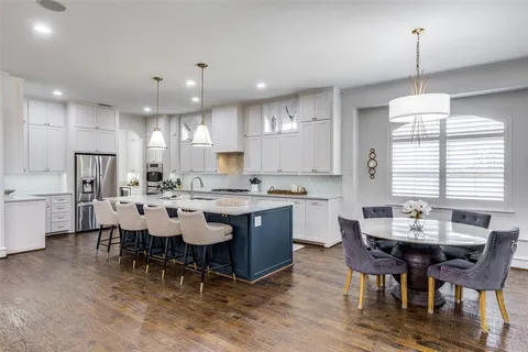a dining room with stainless steel appliances kitchen island granite countertop a dining table chairs and sink