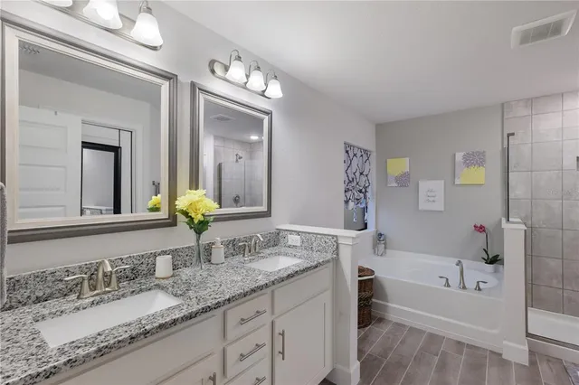 a bathroom with a granite countertop tub a double vanity sink and a mirror