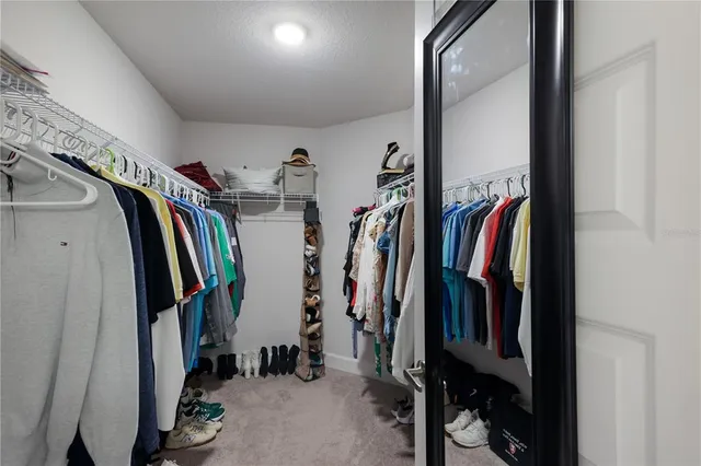 a view of walk in closet with clothes and shoes