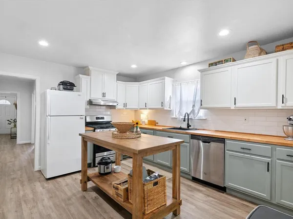 a kitchen with a sink a stove a refrigerator and white cabinets