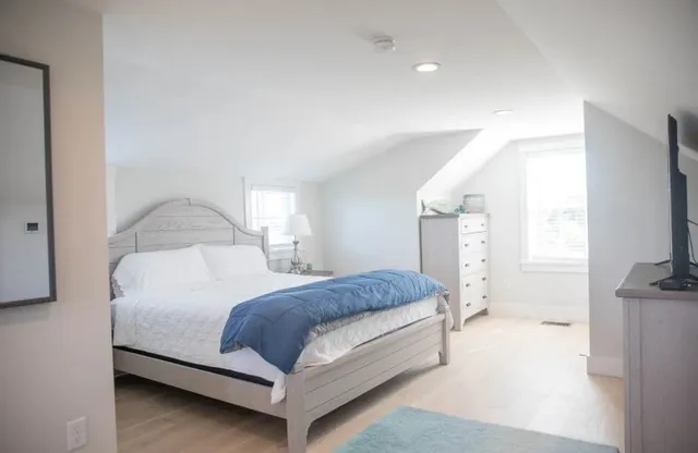 a bedroom with a bed and a flat tv screen on dresser