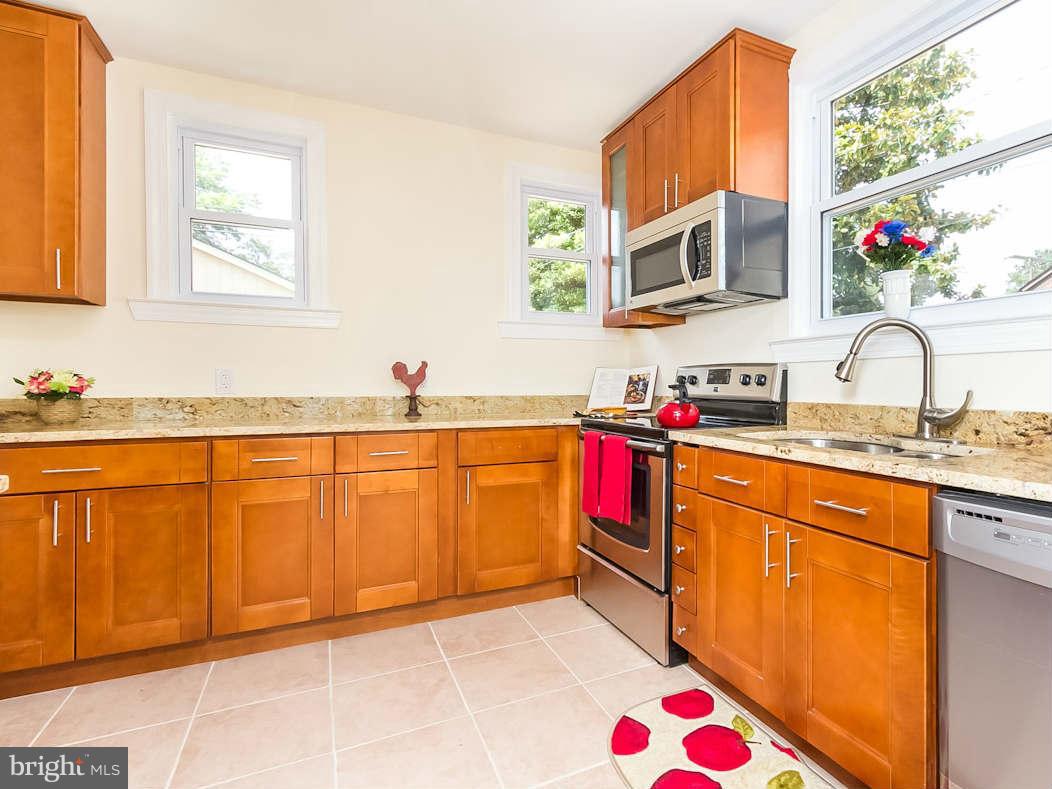 5006 Levindale Road Baltimore, MD 21215 - Photo 9 of 23 a kitchen with stainless steel appliances granite countertop a sink dishwasher and cabinets with wooden floor