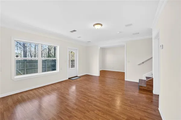 a view of an empty room with wooden floor and a window