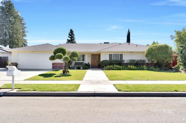 a front view of a house with a yard and potted plants