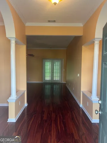 a view of empty room with wooden floor and fan