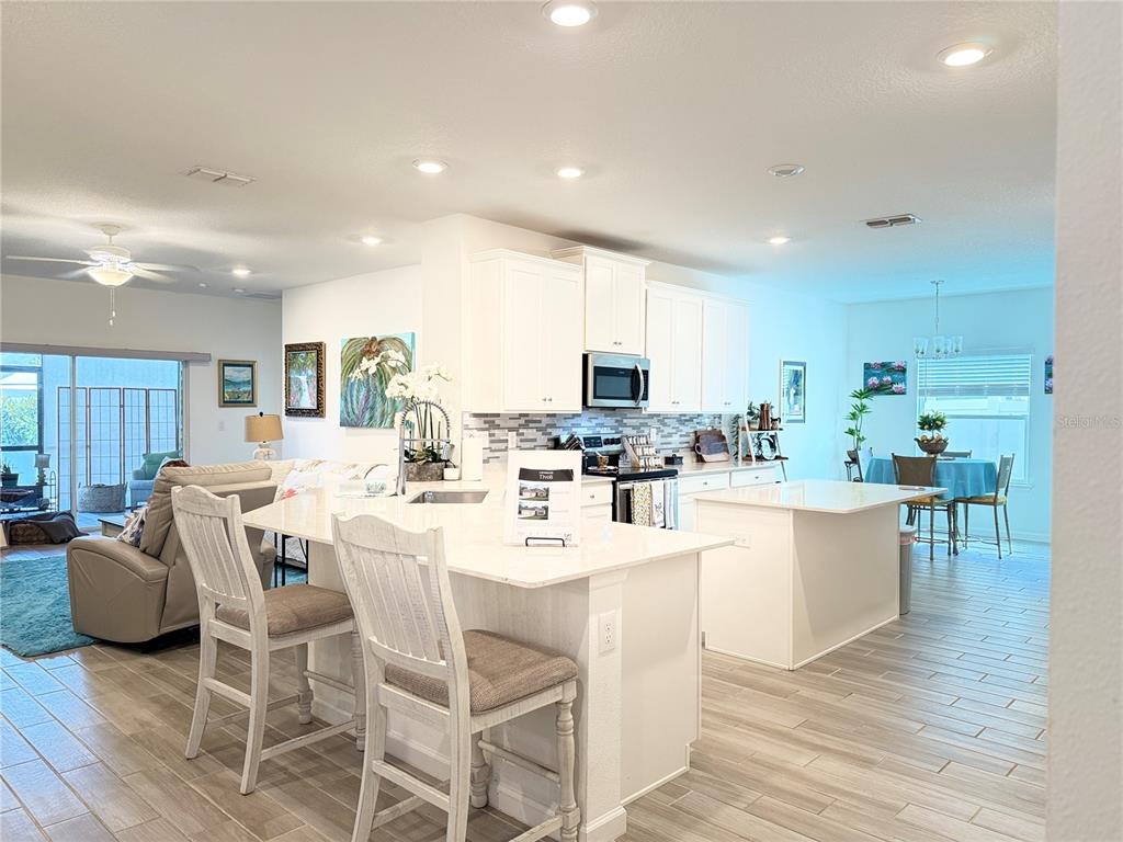 7656 Southwest 74th Loop Ocala, FL 34474 - Photo 23 of 95 a kitchen with stainless steel appliances kitchen island granite countertop a stove a sink a dining table and chairs
