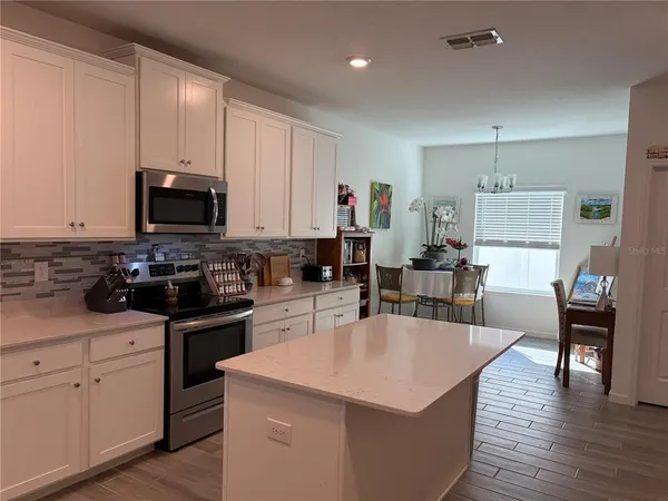 a kitchen with granite countertop a stove a sink a dining table and chairs