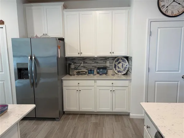 a kitchen with stainless steel appliances granite countertop a refrigerator a stove and white cabinets with wooden floor