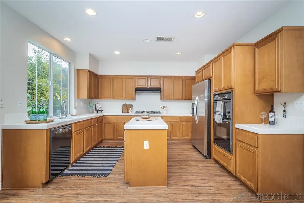 1088 Greenway Road Oceanside, CA 92057 - Photo 6 of 25 a kitchen with stainless steel appliances granite countertop a stove top oven a refrigerator a sink and dishwasher with wooden floor