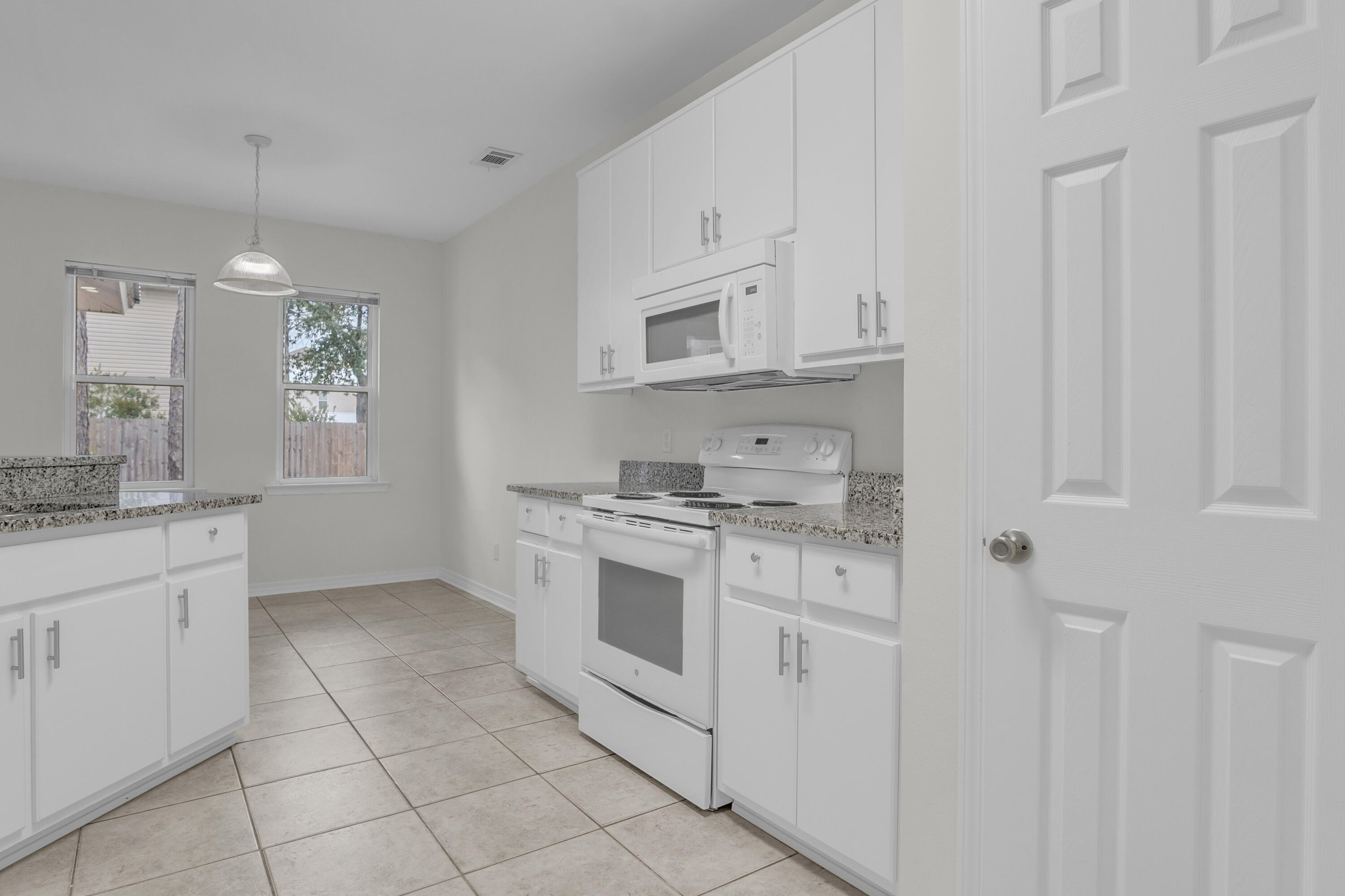 63 Las Roblas Grande Drive Santa Rosa Beach, FL 32459 - Photo 21 of 28 a kitchen with granite countertop white cabinets and white appliances
