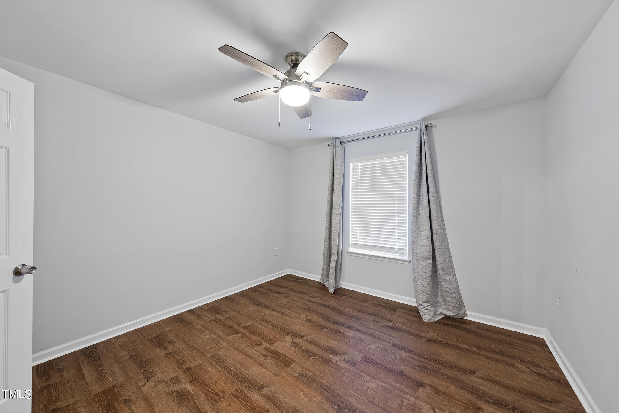 1309 Hillbrow Lane, Unit 103 Raleigh, NC 27615 - Photo 19 of 25 a view of an empty room with wooden floor and a ceiling fan